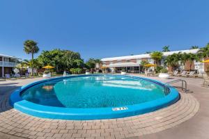 una gran piscina en un complejo con sillas y sombrillas en Best Western Palm Beach Lakes en West Palm Beach