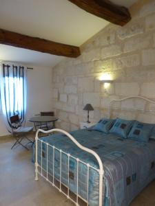 um quarto com uma cama e uma parede de pedra em Le Mas d'Isnard em Arles