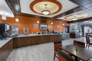 a large room with tables and a kitchen with orange walls at Best Western Plus Fort Stockton Hotel in Fort Stockton