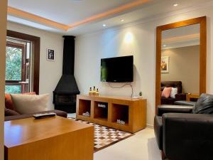sala de estar con TV y chimenea en Apartamentos GRUNENBERG a 5 min do CENTRO by Achei Gramado, en Gramado