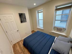 um quarto com uma cama azul e uma janela em New Apartament one Single Ride from Manhattan.. em Long Island City