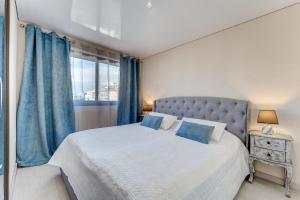 a bedroom with a bed with blue curtains and a window at BuenaVista Lago La Arena in Puerto de Santiago +36 photos