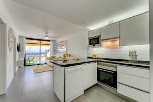 a kitchen with white cabinets and a view of the ocean at BuenaVista Sunflower Apartment in Playa La Arena in Puerto de Santiago
