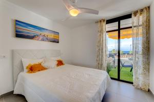 biała sypialnia z łóżkiem i oknem w obiekcie BuenaVista Sunflower Apartment in Playa La Arena w mieście Puerto de Santiago +37 zdjęć