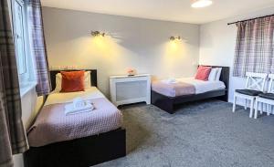 Habitación pequeña con 2 camas y mesa. en Broadford House Skye en Broadford