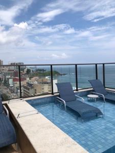 un balcón con 2 sillas y una piscina en Vista Panorâmica, Conforto e Piscina à Beira-Mar, en Salvador