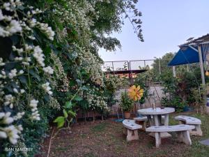 a picnic table and benches in a garden with flowers at Ban Maitree in Chiang Mai