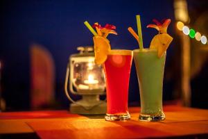 two cocktails sitting on a table with a candle at Secret Garden Beach Resort in Bangrak Beach