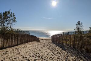 einen Sandstrand mit einem Zaun und dem Meer in der Unterkunft Spacious quiet nest with garden near the sea in La Tranche-sur-Mer