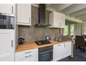 Una cocina con gabinetes blancos y un horno de estufa. en Family House in Vrouwenpolder near Beach, en Vrouwenpolder