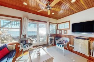 a living room with a ceiling fan and a flat screen tv at Commercial Street Retreat in Provincetown