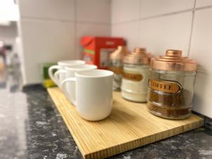 a row of coffee cups on a wooden cutting board at Entire 3 Bedroom House- FREE PARKING in Liverpool