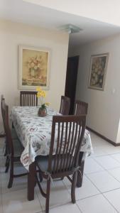 una mesa de comedor con sillas y un jarrón de flores. en Condominio Chateau Mondrian en Cabo Frío