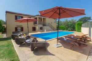 einen Pool mit Sonnenschirmen und Stühlen sowie einem Tisch und Stühlen in der Unterkunft Apartments in Porec - Istrien 43248 in Poreč