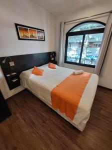 a bedroom with a large bed with an orange blanket at Posada Los Pinos in Colonia del Sacramento