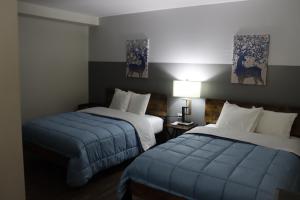 um quarto de hotel com duas camas com capas azuis em Timberland Inn & Restaurant em Swan River