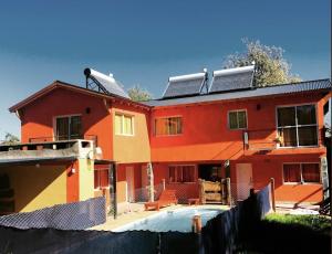 una casa roja con una piscina frente a ella en Posada The Gringos en Villa Yacanto