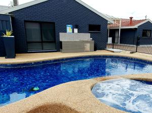 a large swimming pool in front of a house at Addison Motor Inn in Shepparton