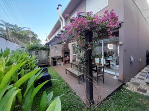 un jardin avec des fleurs roses sur une maison dans l'établissement Pé na areia em Boiçucanga condominio Aquamarine - perto de Maresias e Camburi, à Boicucanga