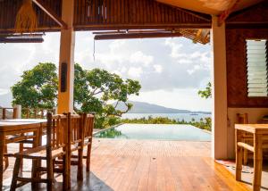een patio met een tafel en stoelen en uitzicht op het water bij Ocean Green Eco Lodge in Puerto Princesa City