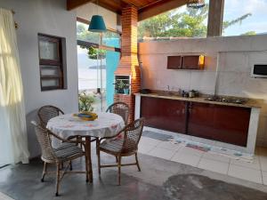 a dining room with a table and chairs and a kitchen at Casa na praia em São Sebastião in São Sebastião