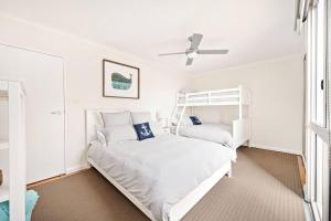 a white bedroom with a bunk bed and a ceiling fan at The Crest in Shoal Bay