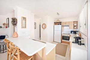 a kitchen with white appliances and a white table at The Crest in Shoal Bay