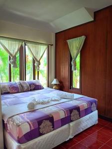 ein großes Bett in einem Schlafzimmer mit Fenstern in der Unterkunft Apache Bar Haad yao in Haad Yao