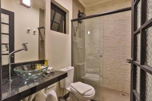 La salle de bains est pourvue de toilettes et d'une douche en verre. dans l'établissement Pousada Terrazzo Bonjardim, à Campos do Jordão