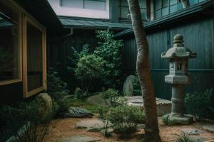 a japanese garden with a bird bath next to a house at TANIYA in Takayama