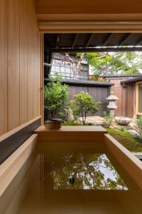 ein kleiner Teich in der Ecke eines Hauses mit Fenster in der Unterkunft TANIYA in Takayama