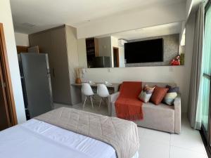 een slaapkamer met een bed, een bank en een tv bij Mana Beach Sol by Vivere Flats in Porto De Galinhas