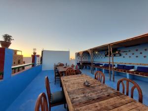 タガズートにあるOrca Surf Houseの屋根に木製のテーブルと椅子を配したレストラン