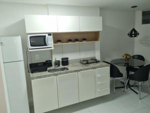 cocina con fregadero, microondas y mesa en Espetacular Flat Miramar 4, en João Pessoa