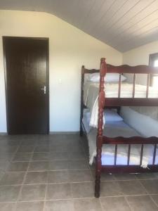 a room with two bunk beds and a black door at Kantinho do Mar in São Francisco do Sul