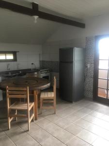 a kitchen with a table and chairs and a refrigerator at Kantinho do Mar in São Francisco do Sul