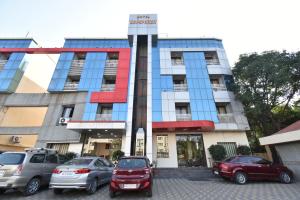 un edificio con coches estacionados frente a él en Hotel Sai Sparsh, en Shirdi