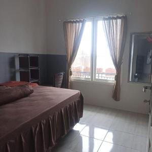 a bedroom with a bed and a large window at Vila Keluarga New ASFA in Batu