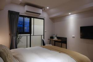 a bedroom with a bed and a tv and a window at Giant Rich Hotel in Taipei