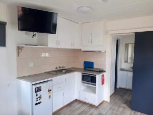 cocina con armarios blancos, fregadero y microondas en Western Plains Tourist Park - Dubbo en Dubbo