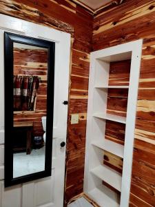 a bathroom with wooden walls and a door with shelves at Log Cabin Inn in Eureka Springs