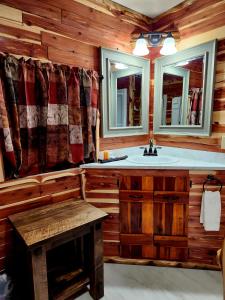 ein Badezimmer mit einem Waschbecken, 2 Spiegeln und einer Bank in der Unterkunft Log Cabin Inn in Eureka Springs