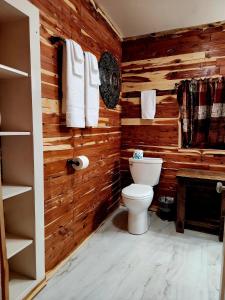 a bathroom with wooden walls and a toilet and towels at Log Cabin Inn in Eureka Springs