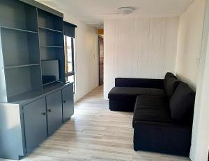 sala de estar con sofá negro y cocina en Western Plains Tourist Park - Dubbo en Dubbo