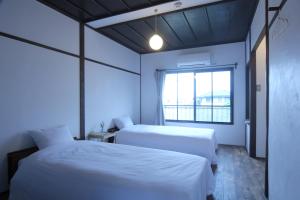 dwa łóżka w pokoju z oknem w obiekcie 淡路島西海岸の宿 梅木屋 w mieście Sumoto
