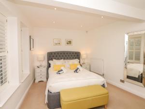 a bedroom with a large bed and a yellow stool at 10 Cove View in Ilfracombe
