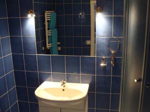 ソポトにあるAqua1000の青いタイル張りのバスルーム(シンク、鏡付)