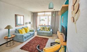 a living room with a blue couch and yellow pillows at 65 @ Zeezicht in Kingsburgh