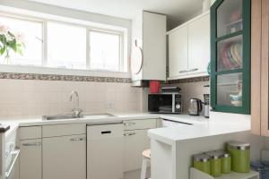 eine weiße Küche mit weißen Schränken und einem Waschbecken in der Unterkunft Beautiful 3BD Flat in Archway London in London