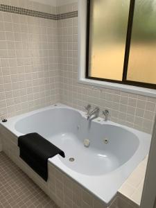 a white bath tub with a black towel on it at The Hideaway Jervis Bay in Vincentia +15 photos